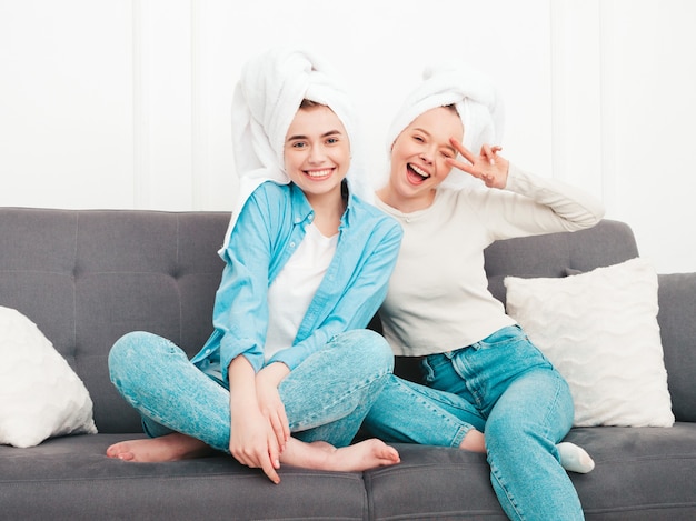 Dos jóvenes hermosas mujeres sonrientes sentadas en el sofá