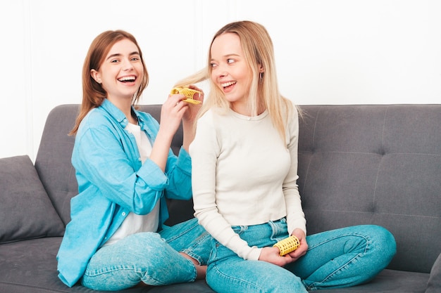 Dos jóvenes hermosas mujeres sonrientes sentadas en el sofá