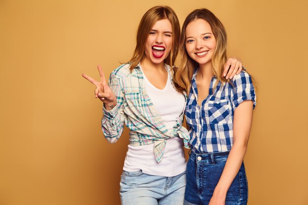 Dos jóvenes hermosas rubias sonrientes en camisas a cuadros de verano de moda