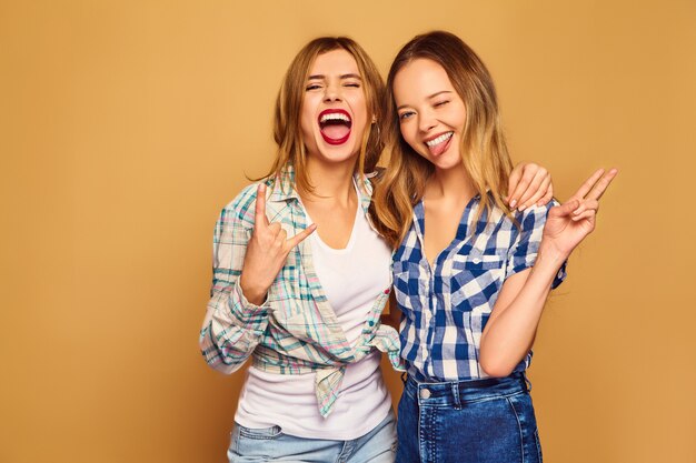 Dos jóvenes hermosas rubias sonrientes en camisas a cuadros de verano de moda