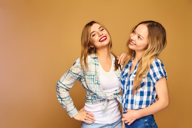 Dos jóvenes hermosas rubias sonrientes en camisas a cuadros de verano de moda