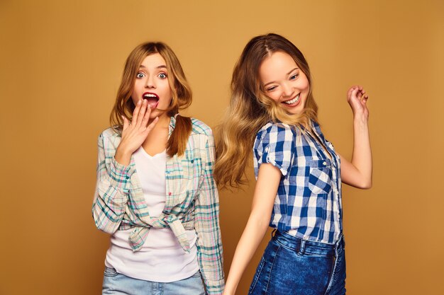 Dos jóvenes hermosas rubias sonrientes en camisas a cuadros de verano de moda