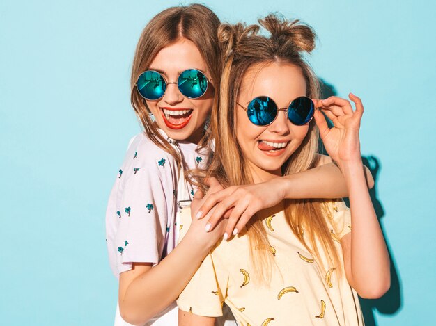 Dos jóvenes hermosas sonrientes rubias hipster chicas en jeans moda verano faldas ropa. y mostrando la lengua