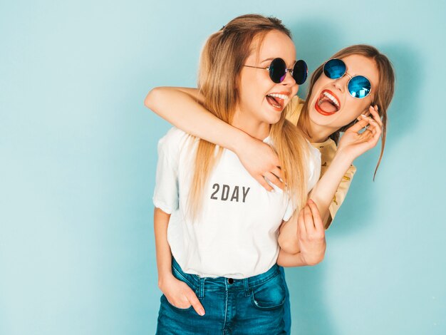 Dos jóvenes hermosas sonrientes rubias hipster chicas en jeans moda verano faldas ropa.