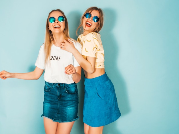 Dos jóvenes hermosas sonrientes rubias hipster chicas en jeans moda verano faldas ropa.