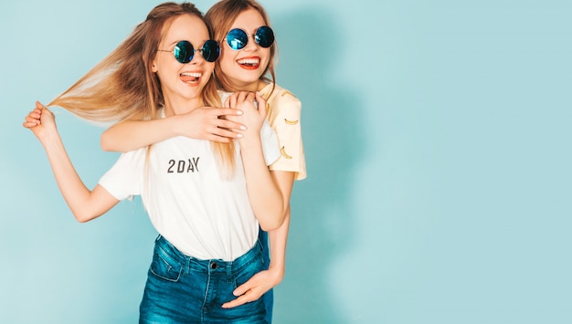 Dos jóvenes hermosas sonrientes rubias hipster chicas en ropa colorida moda verano.