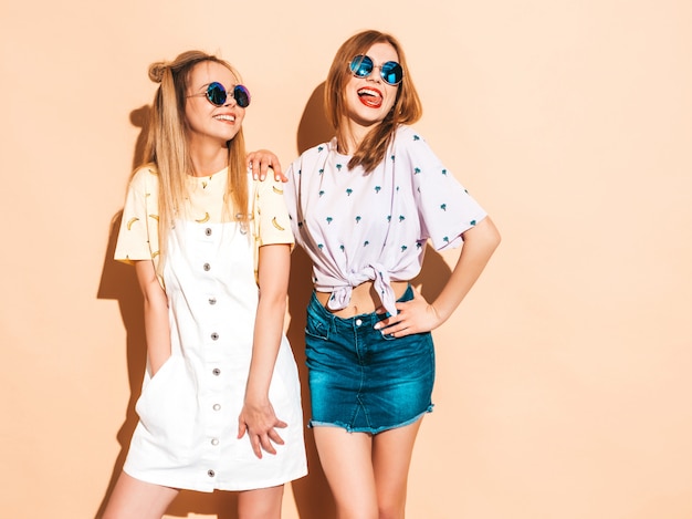 Dos jóvenes hermosas sonrientes rubias hipster chicas en ropa de verano colorida camiseta.