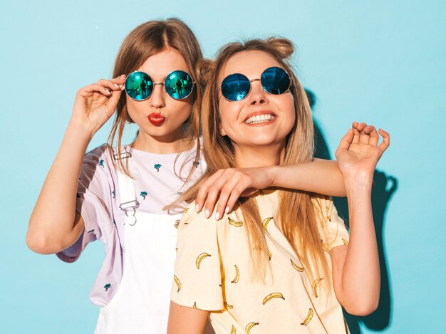 Dos jóvenes hermosas sonrientes rubias hipster chicas en ropa de verano colorida camiseta.