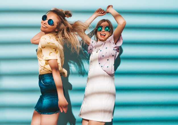 Dos jóvenes hermosas sonrientes rubias hipster chicas en ropa de verano colorida camiseta.