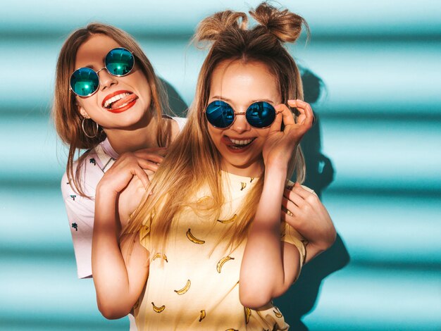 Dos jóvenes hermosas sonrientes rubias hipster chicas en ropa de verano colorida camiseta.