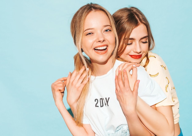 Dos jóvenes hermosas sonrientes rubias hipster chicas en ropa de verano colorida camiseta.