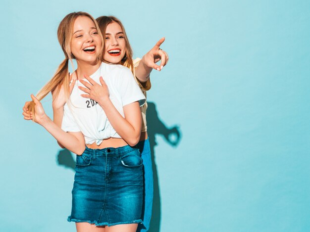 Dos jóvenes hermosas sonrientes rubias hipster chicas en ropa de verano colorida camiseta.