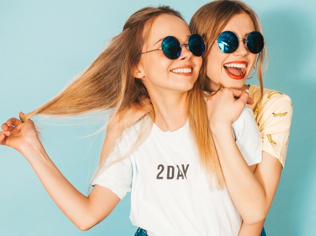 Dos jóvenes hermosas sonrientes rubias hipster chicas en ropa de verano colorida camiseta.