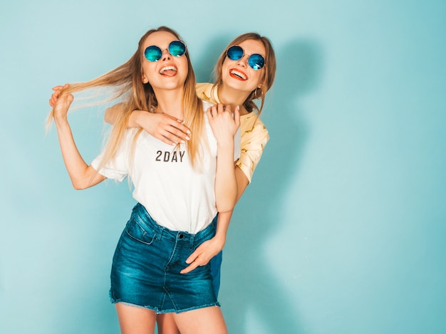 Dos jóvenes hermosas sonrientes rubias hipster chicas en ropa de verano colorida camiseta.