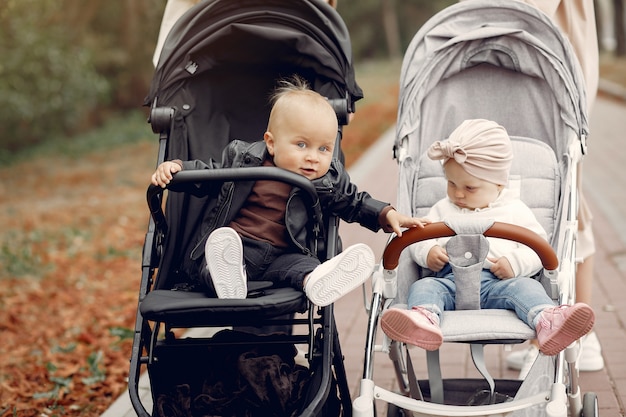 Dos jóvenes madres caminando en un parque de otoño con carruajes