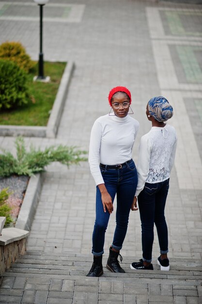 Dos jóvenes mujeres musulmanas africanas altas y delgadas, atractivas, modernas y modernas, con hiyab o pañuelo en la cabeza con turbante, posaron juntas