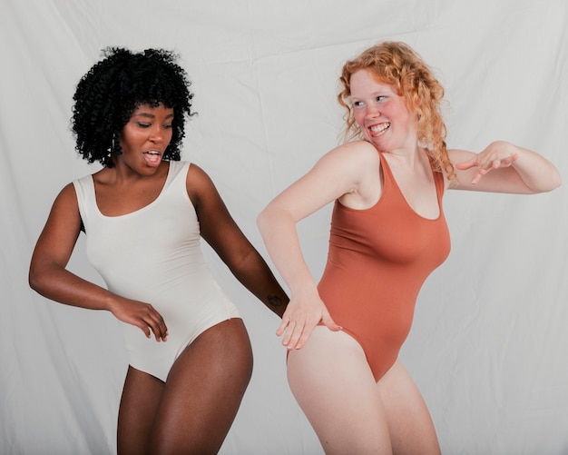 Dos jóvenes multi étnicas mujeres bailando contra el fondo gris