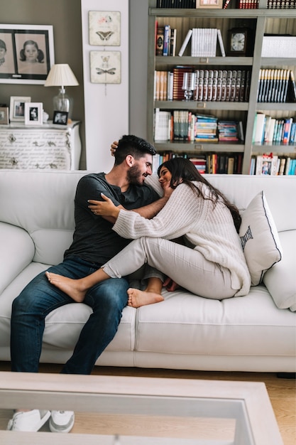 Foto gratuita dos jóvenes pareja sentada en el sofá haciendo el amor en la casa moderna