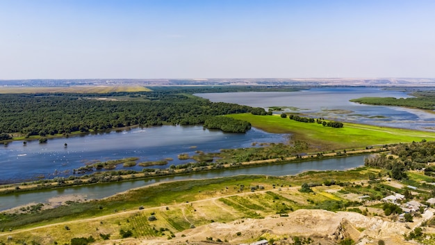 Dos lagos con bosque y campo verde dividiéndolos, camino rural que pasa cerca