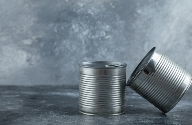 Dos latas colocadas sobre mármol.