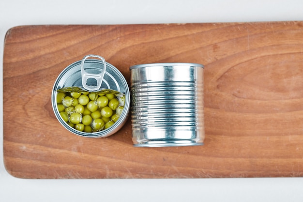 Foto gratuita dos latas de guisantes hervidos sobre una tabla de madera.