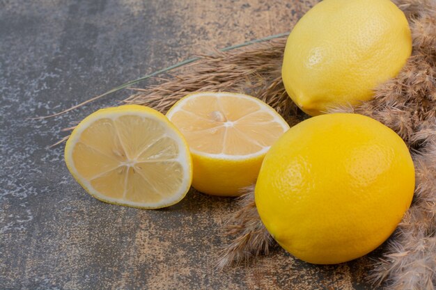 Dos limones frescos enteros con una rodaja en el espacio de mármol