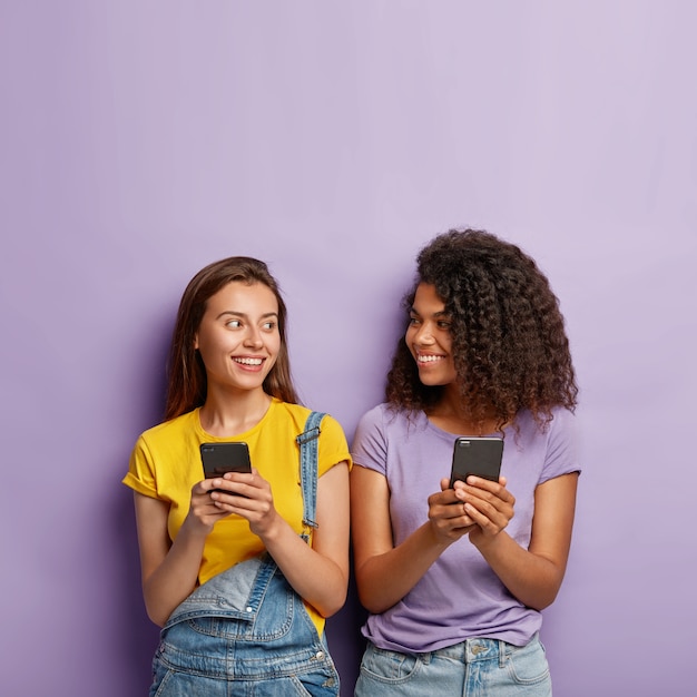 Foto gratuita dos lindas chicas milenarias usan teléfonos celulares