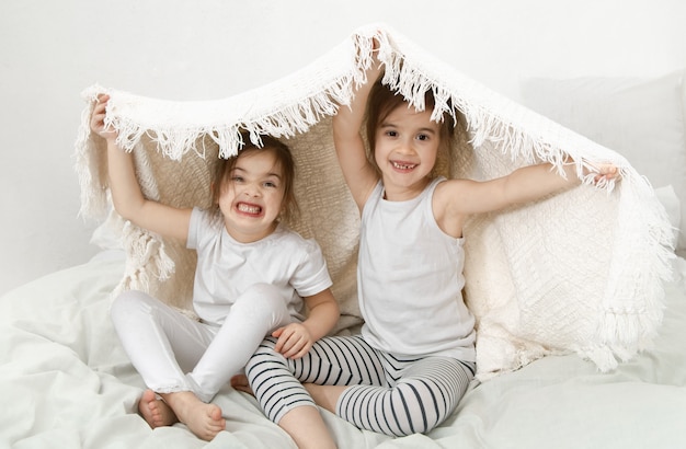 Dos lindas hermanitas se abrazan en la cama del dormitorio.