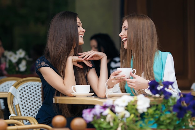 dos lindas mujeres jóvenes en un café con café y teléfono