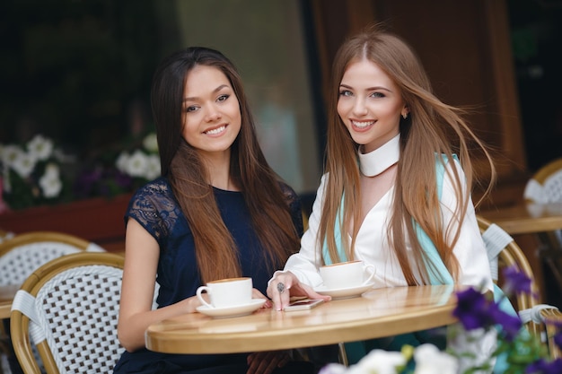 dos lindas mujeres jóvenes en un café con café y teléfono
