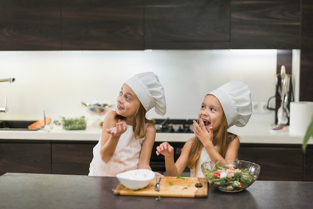 Foto gratuita dos lindos hermanos sonrientes divirtiéndose en la cocina