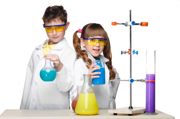 Dos lindos niños en clase de química haciendo experimentos