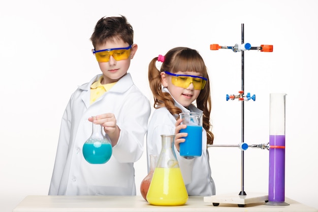 Dos lindos niños en clase de química haciendo experimentos