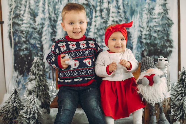 Dos lindos niños sentados en una decoración navideña