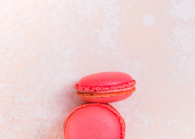 Foto gratuita dos macarrones rosados en fondo texturizado