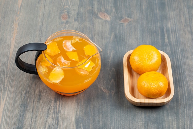 Dos mandarinas frescas con un tarro de jugo de vidrio