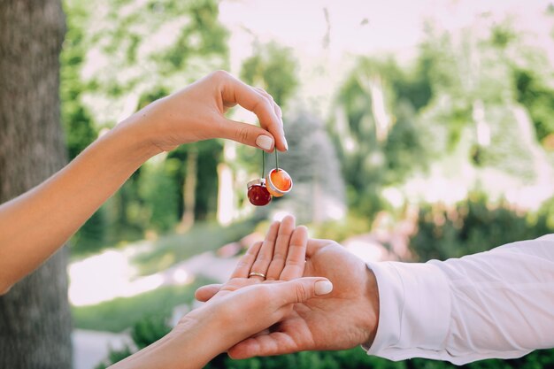 dos manos de amantes y anillos en una doble cereza