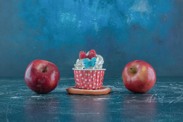 Dos manzanas y una magdalena en una rodaja de pomelo sobre fondo azul. Foto de alta calidad