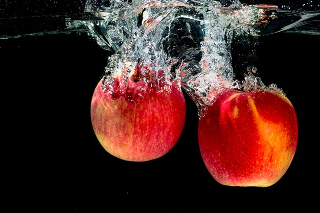 Dos manzanas rojas chapoteando en el agua