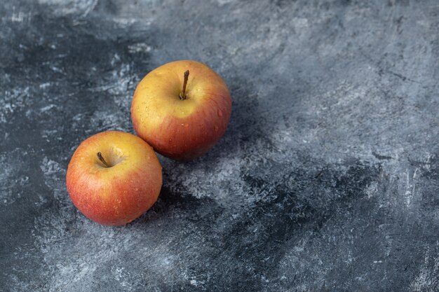 Dos manzanas rojas frescas sobre un fondo de mármol.