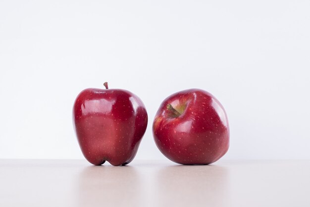 Dos manzanas rojas sobre blanco.