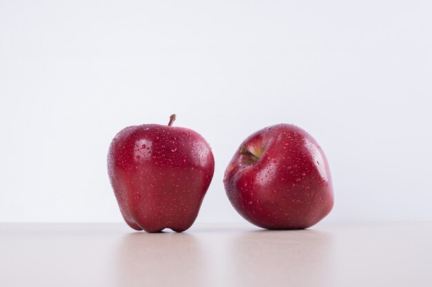 Dos manzanas rojas sobre blanco.