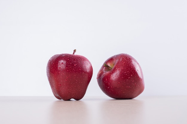 Dos manzanas rojas sobre blanco.