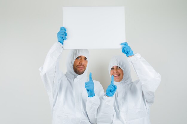 Dos médicos apuntando al lienzo en blanco con trajes protectores