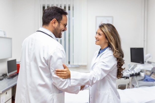 Dos médicos profesionales confiados dándose la mano mientras están de pie en la clínica Trabajo en equipo de la reunión médica caucásica y saludo con un apretón de manos en el hospital Concepto de atención médica del equipo médico