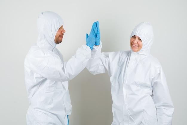 Dos médicos en traje de protección, guantes aplaudiendo y mirando feliz