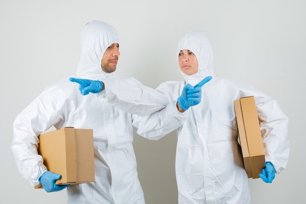 Dos médicos en trajes de protección, guantes con cajas de cartón