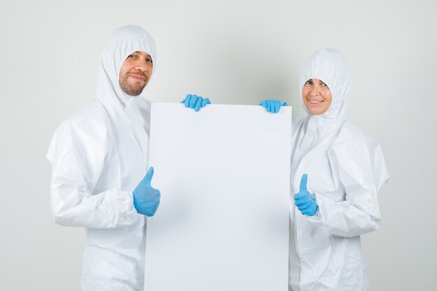 Dos médicos en trajes de protección, guantes con lienzo en blanco