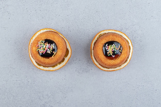 Dos mini tortas con gelatina colocadas encima de una rodaja de naranja. Foto de alta calidad