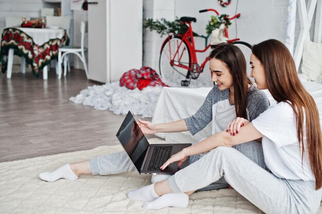 Dos modelos gemelos con laptop en estudio buscando algo